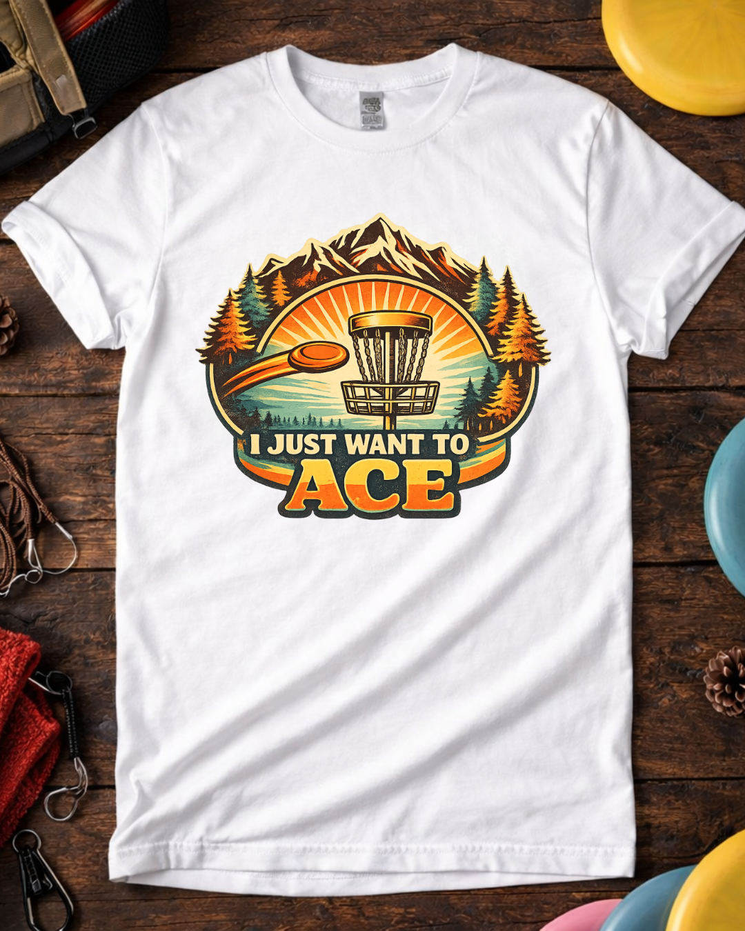 White I Just Want To Ace funny disc golf t-shirt on wooden background.