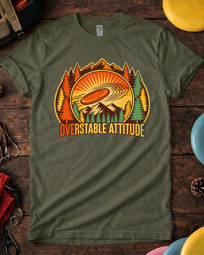 Overstable Attitude disc golf shirt with retro mountains and trees. Overstable Attitude funny disc golf t-shirt on wooden background.